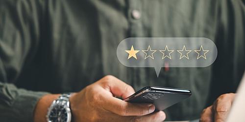 man using a phone and laptop with a graphic floating above showing one out of five stars